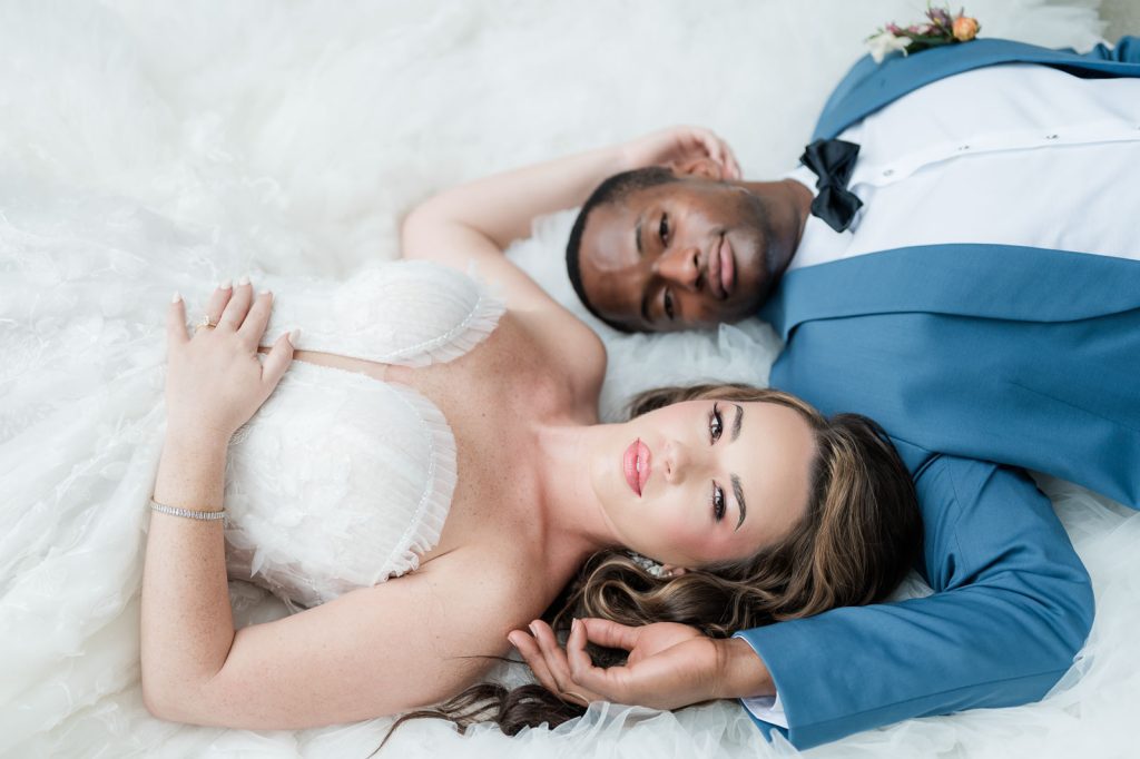 bride and groom laying on tulle of bride's wedding dress