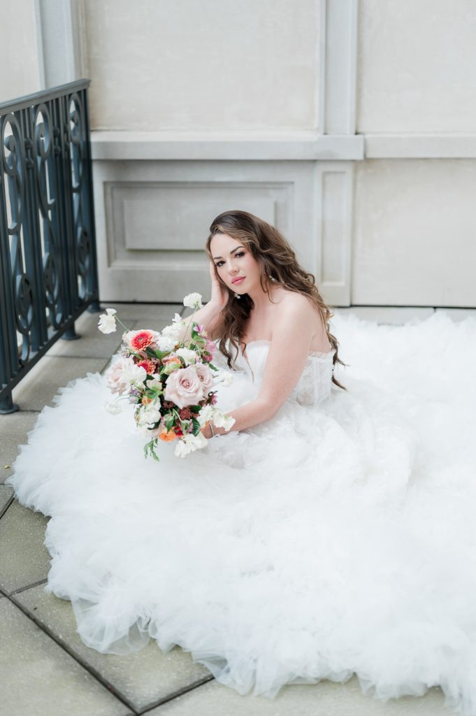 bride sitting down surrounded by tulle of her wedding dress.