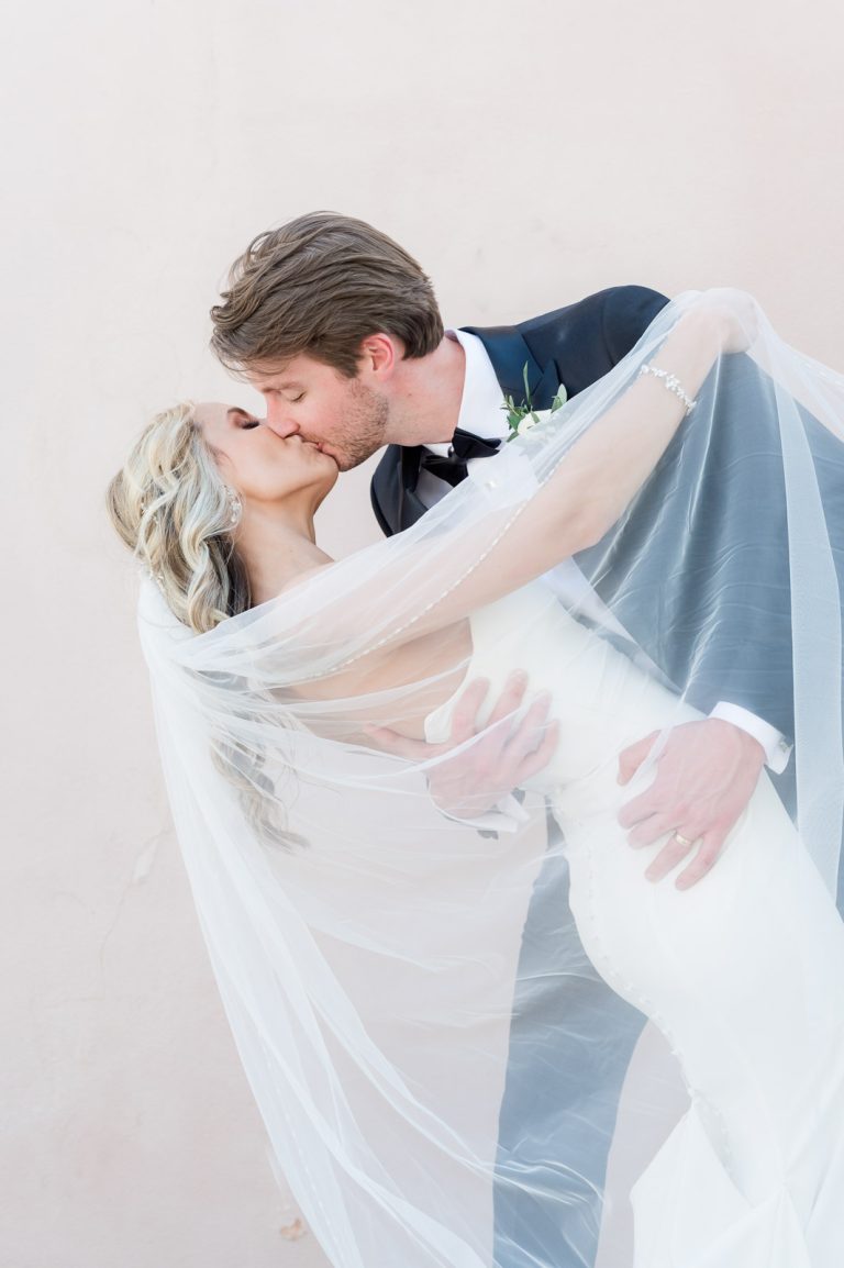 newlyweds kiss and dip while covered in bride's veil