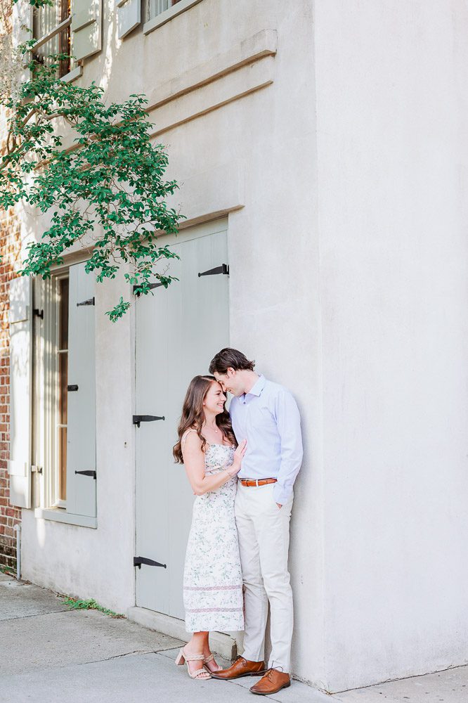 couple lean foreheads together against wall in downtown Charleston