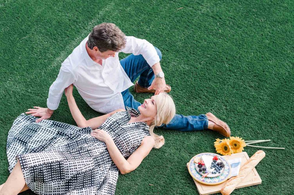 couple laying in grass having picnic
