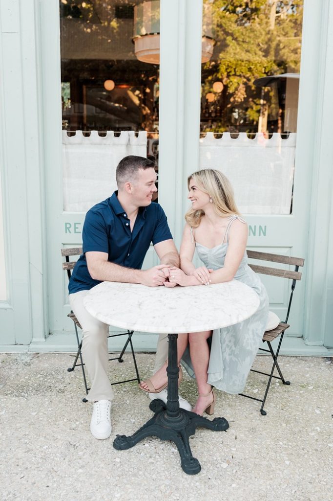 engaged couple hold hands while seated at a table