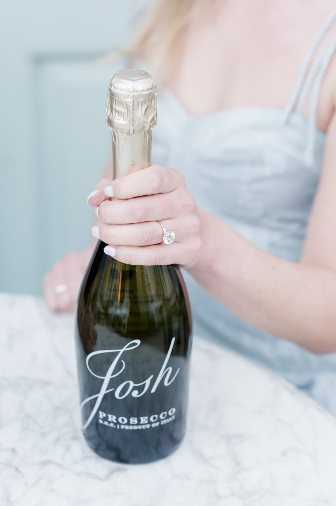 girl holds bottle of Josh prosecco with left hand with engagement ring