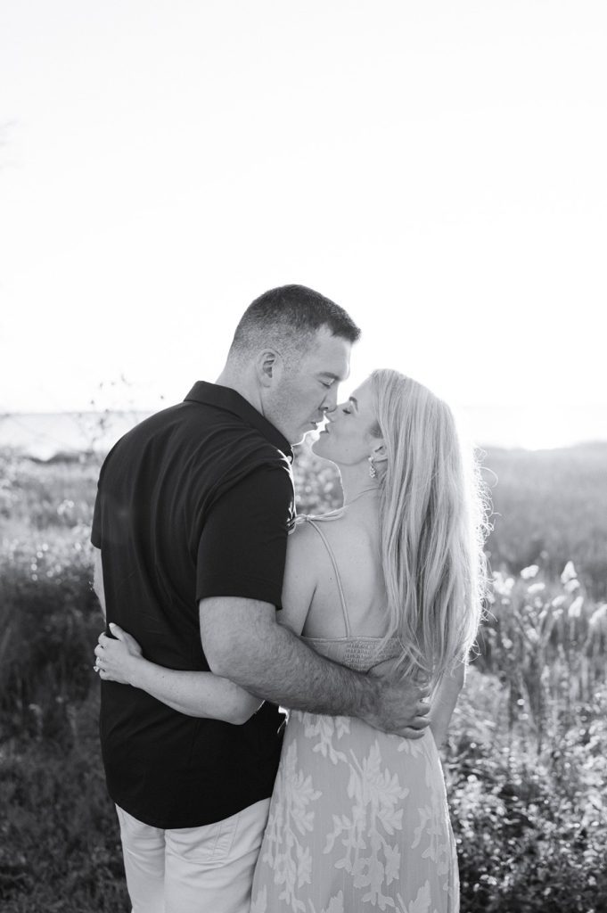 black and white photo of couple with back to camera with arms around each other's backs almost about to kiss