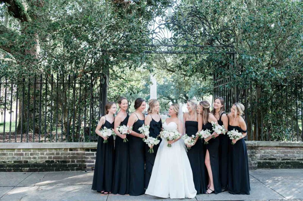 bridesmaids in black dresses with white bouquets lean in close to bride on Chalmers Street