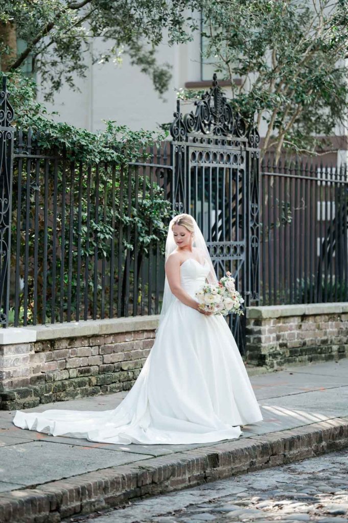 bride looking down shoulder in front of black iron fence. flattering bridal poses