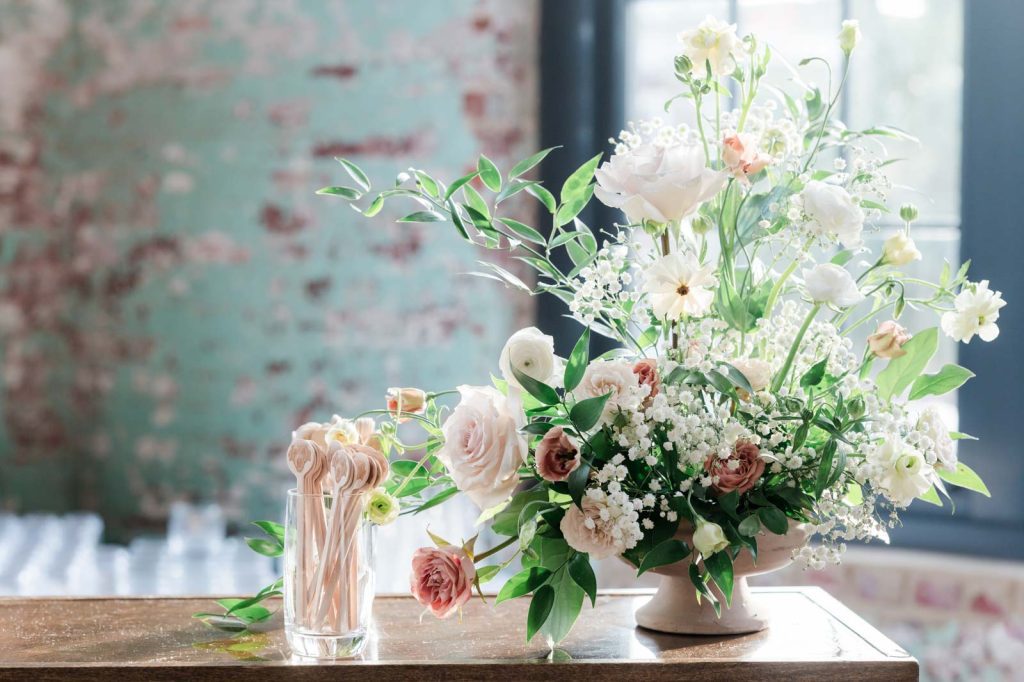 wooden bar with cup of wooden drink stirrers with dog face printed on them and floral arrangement