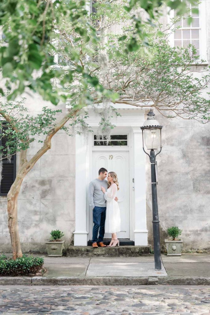 engaged couple stand in door frame facing each other