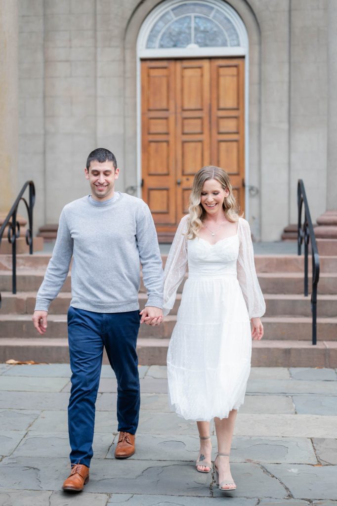 couple both look down while holding hands and walking away from church