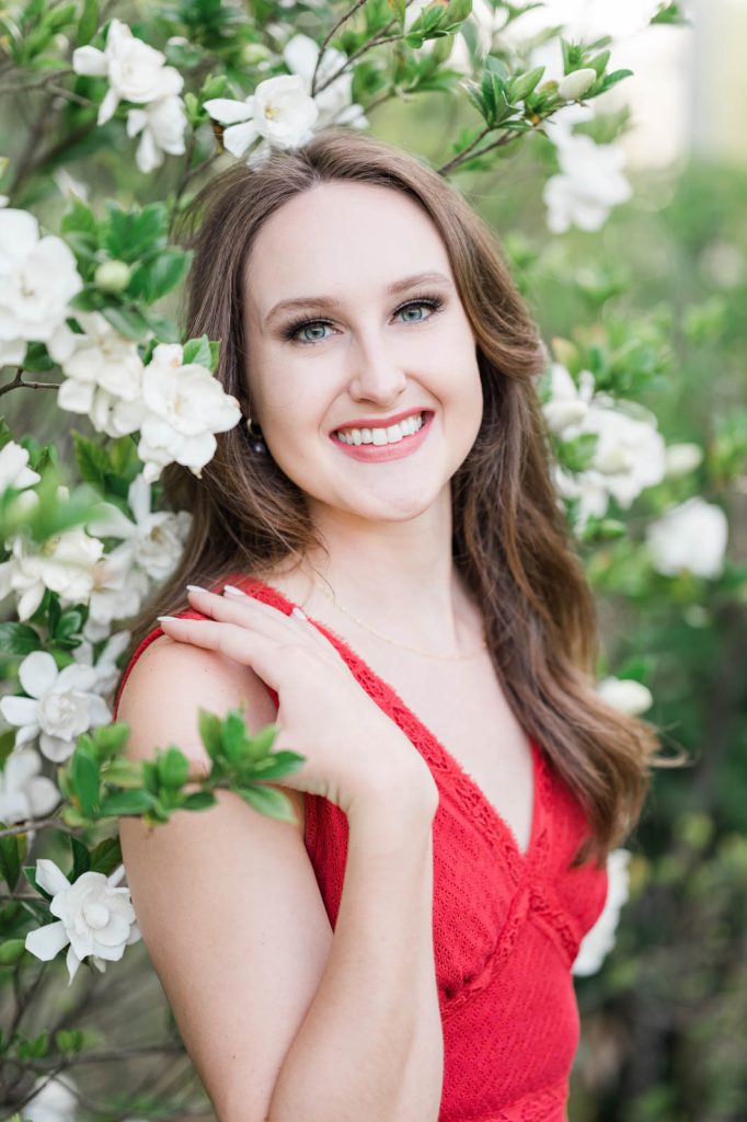 Senior in red dress surrounded by camelia blooms