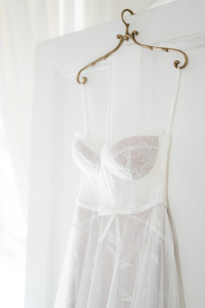 Wedding dress hanging off back of door on gold hanger