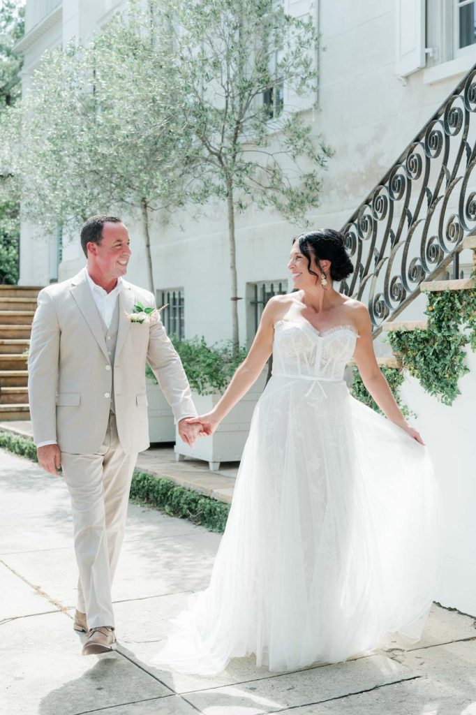 bride and groom hold hands and walk near villa
