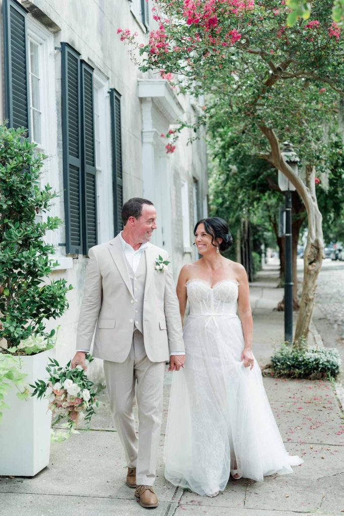 bride and groom look at each other while walking down Charleston street