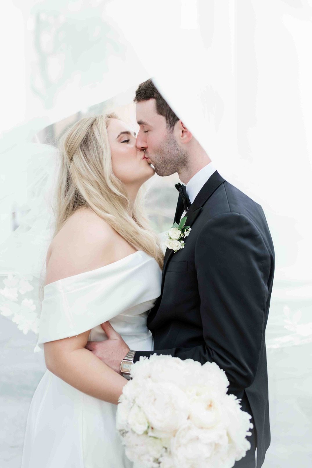 newlywed couple kissing under bride's veil