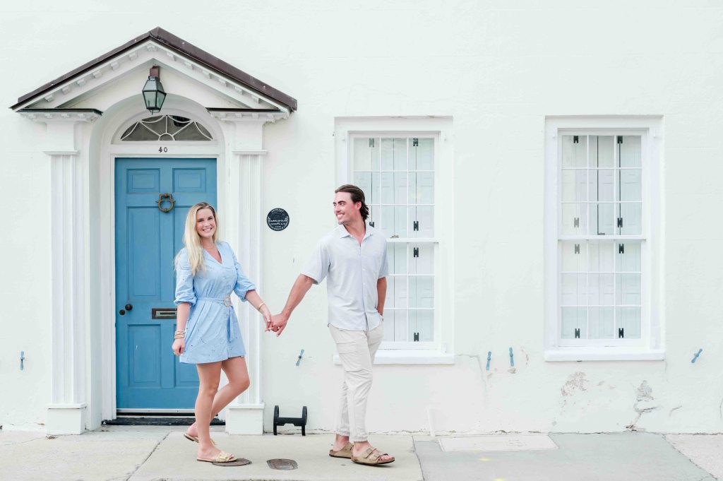 couple stroll down Tradd Street house with blue shutters