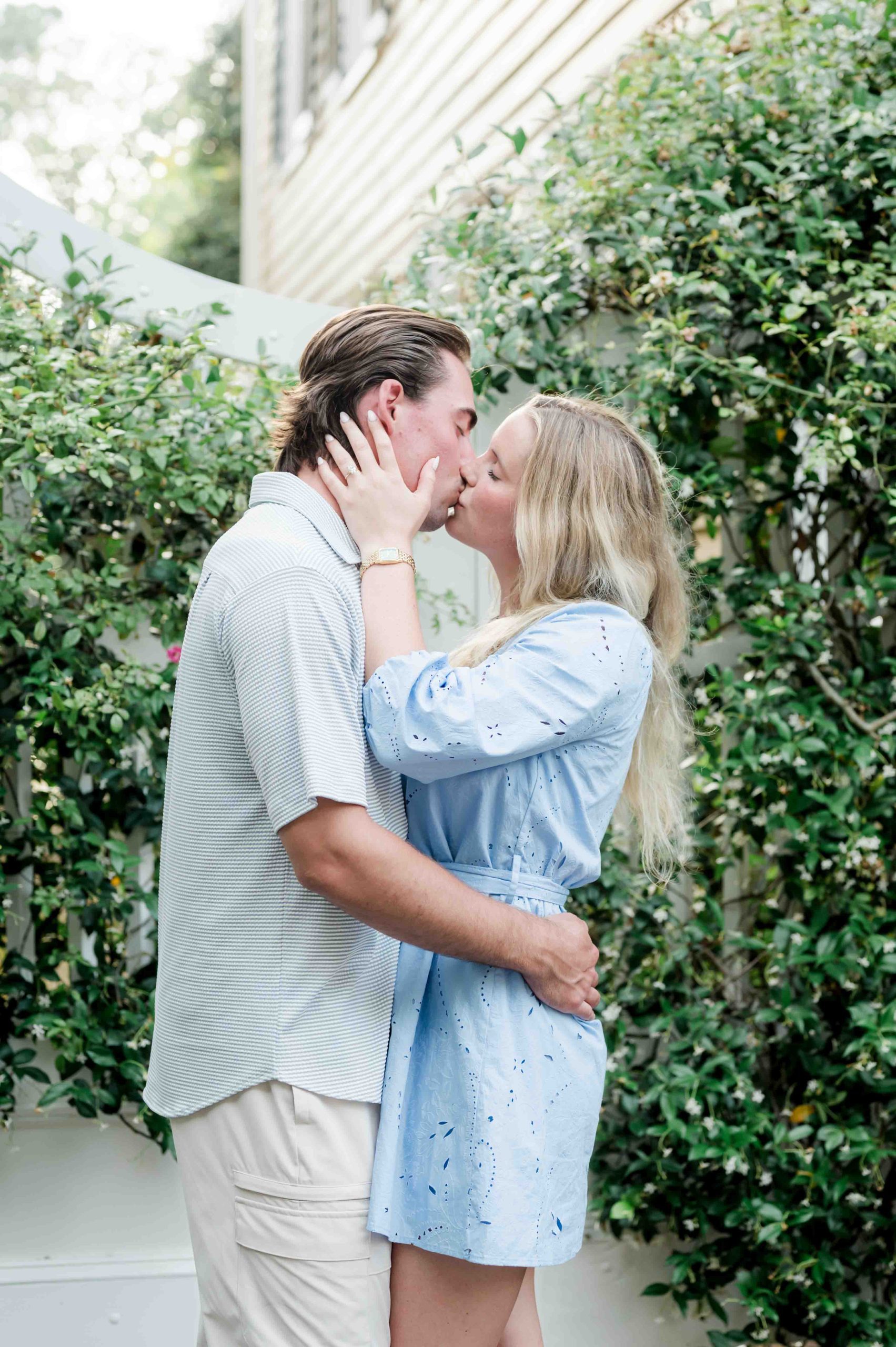 couple kiss in front of greenery covered gate