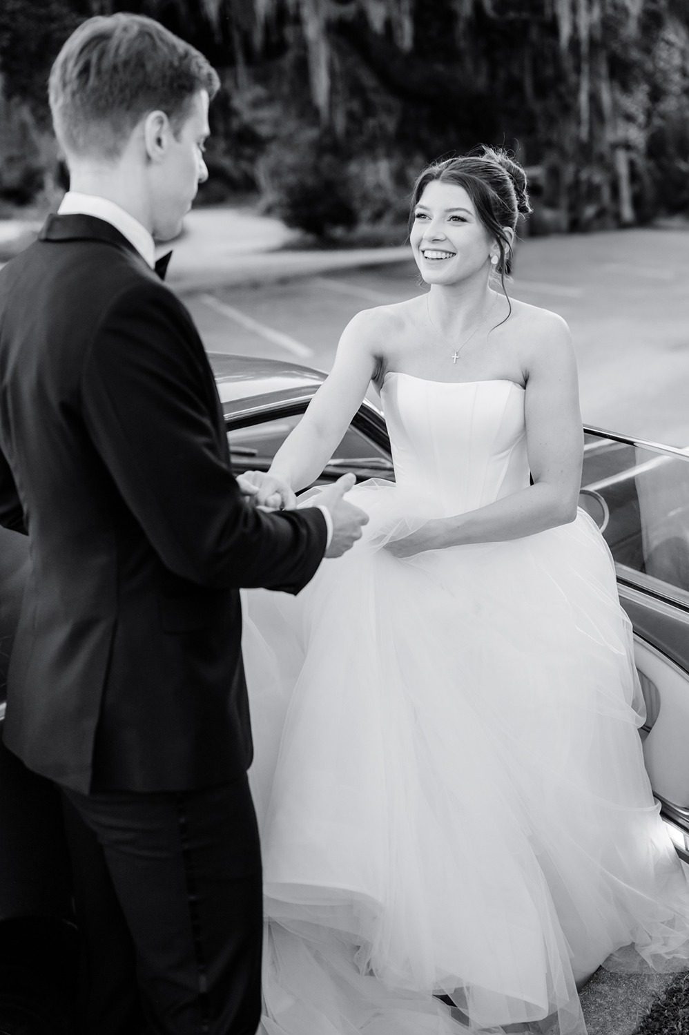 bride bring helped out of mustang while groom holds her hand
