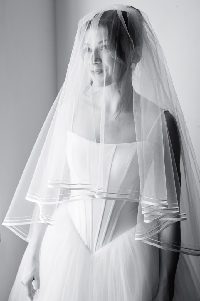 black and white photo of bride looking off camera with veil over bride's face