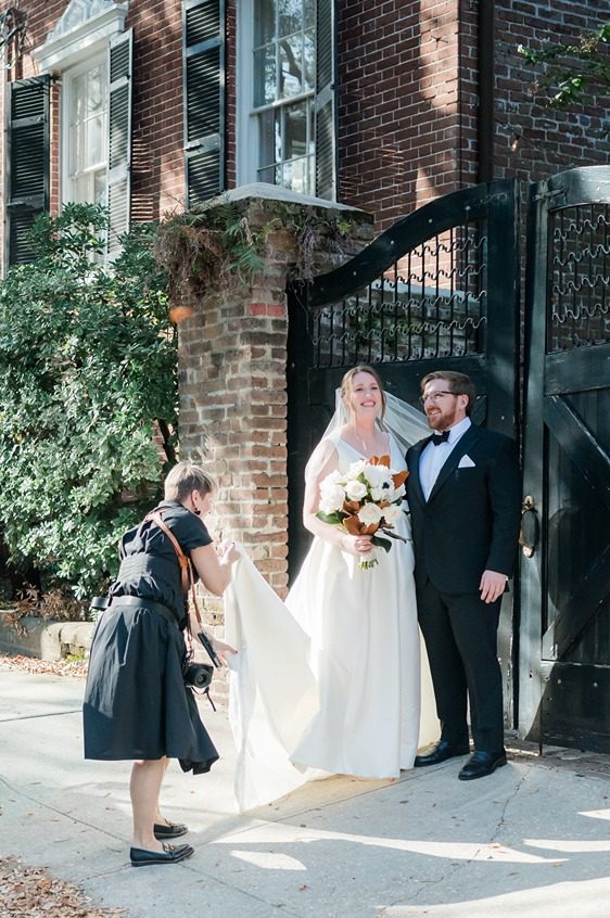 photographer helping with bride's wedding dress