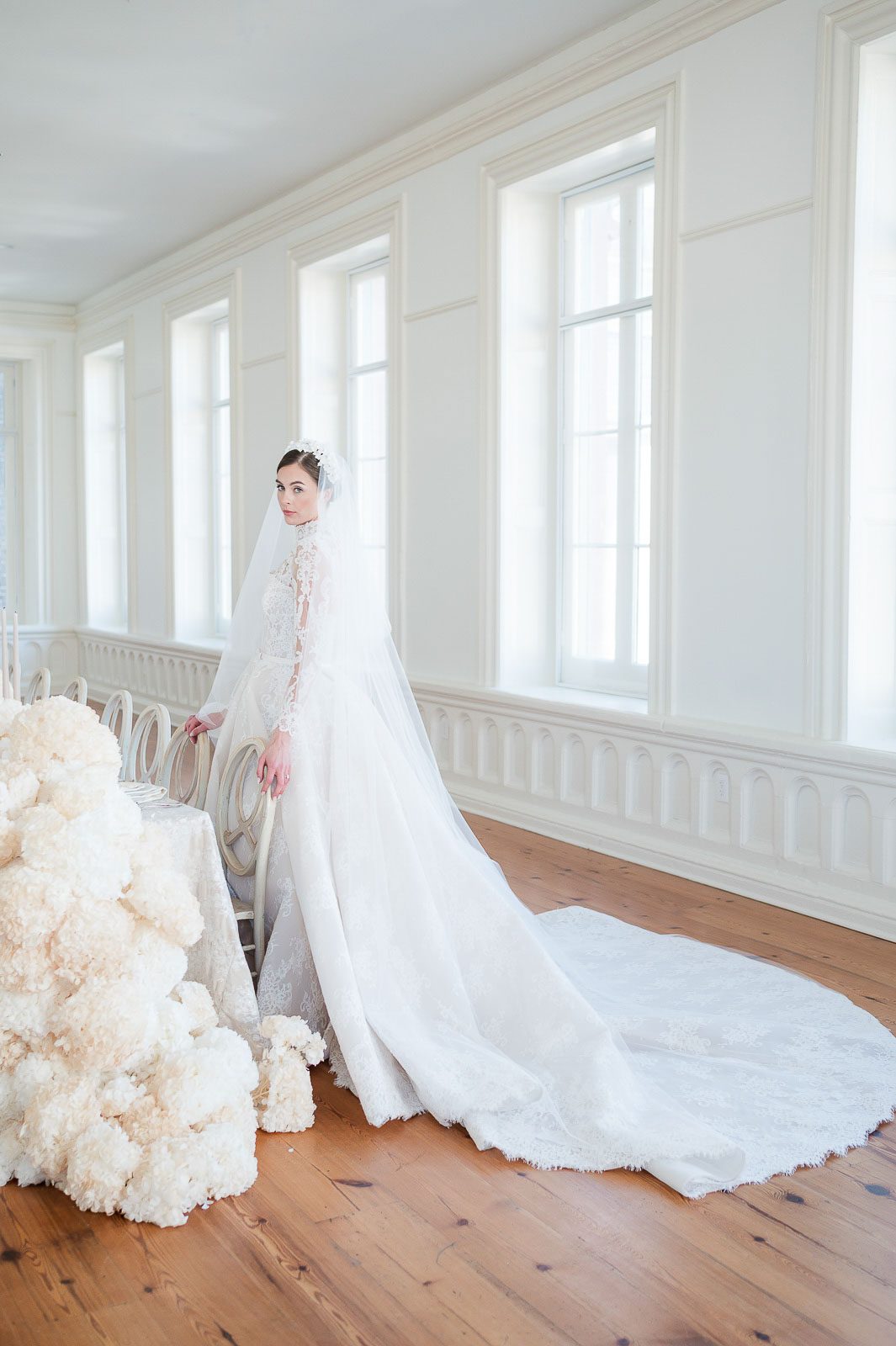 Bride standing in front of an elegant wedding reception table with white florals in Charleston, South Carolina.