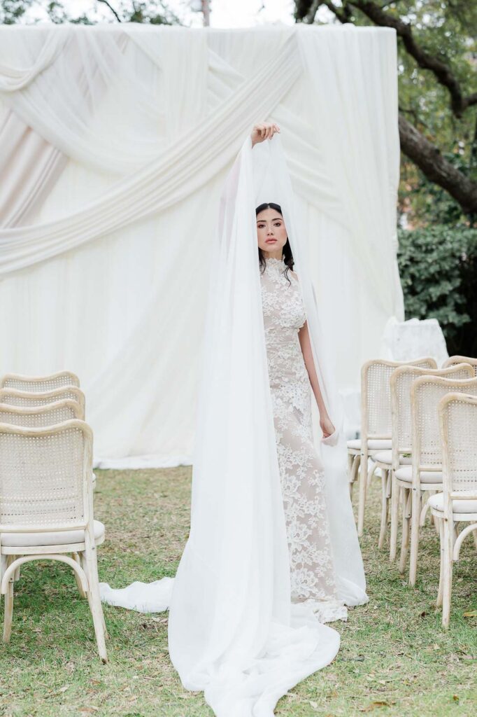 bride standing in front of ceremony altar with white draping