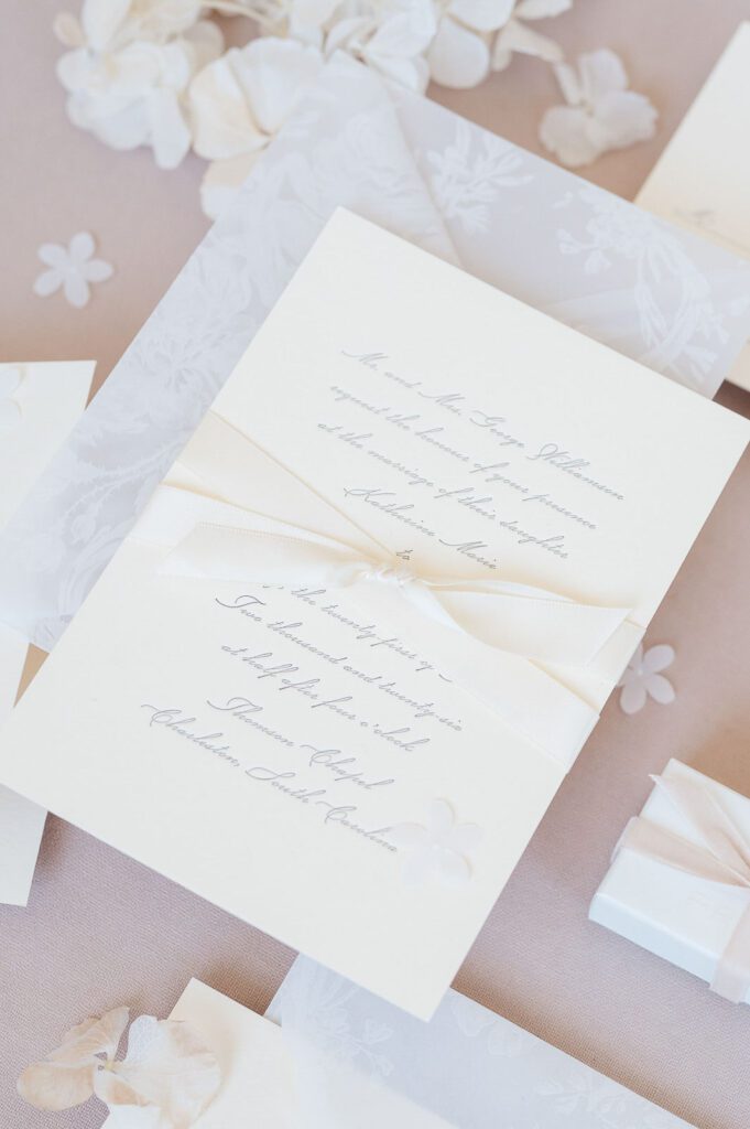 close up of Cream wedding invitation suite on blush flatlay styling by Leigh Hayward Photography