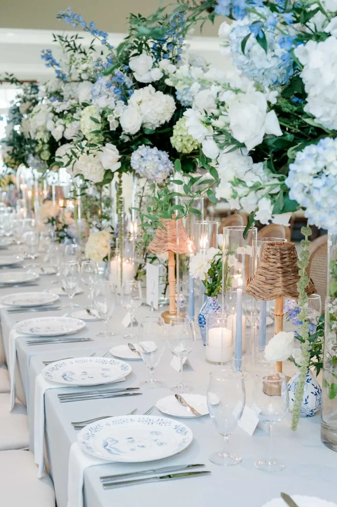 Seabrook Island wedding reception table featuring a table number, lush florals, glowing candles, rattan lamps, and blue and white chinoiserie plates.
