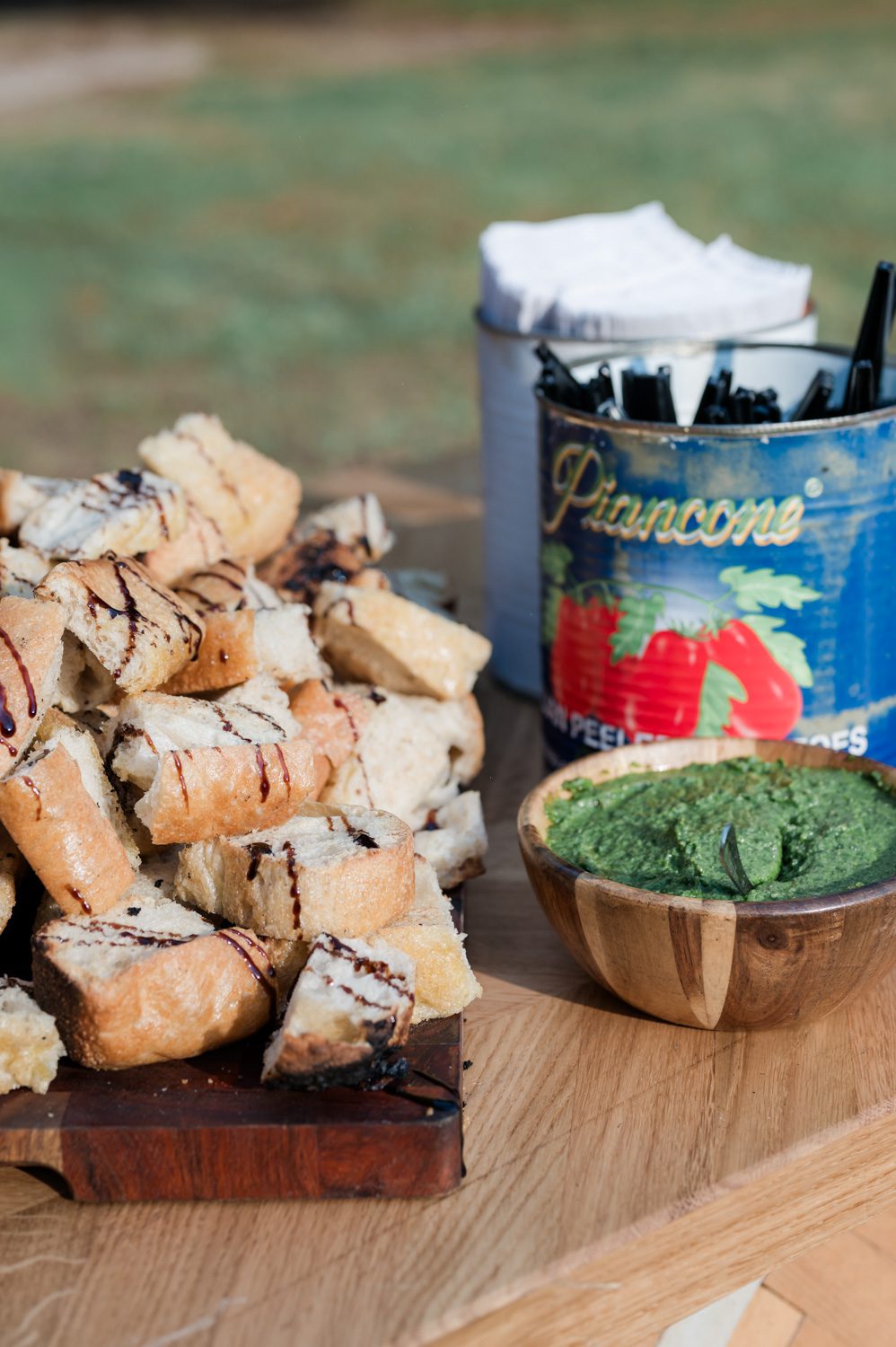 Italian-themed rehearsal dinner tablescape featuring rustic bread drizzled with balsamic vinegar alongside a bowl of fresh pesto, styled for an elegant, intimate celebration.