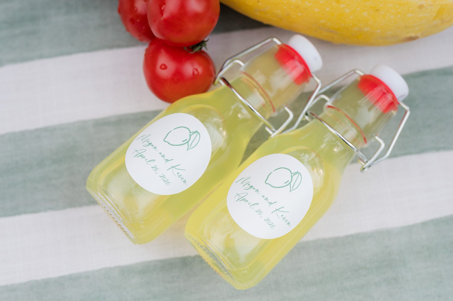 Two miniature bottles of limoncello set on an Italian-themed rehearsal dinner table, styled as a celebratory detail for guests.