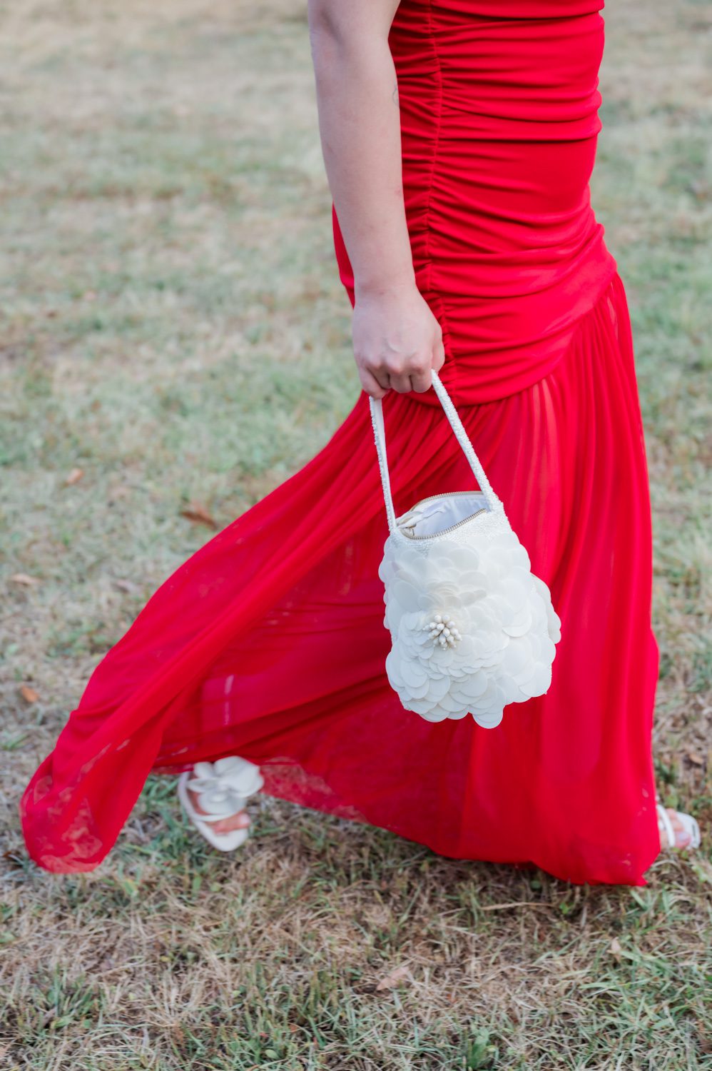 Detail shot of a red dress paired with a white purse at an Italian-themed rehearsal dinner at Middleton Place, featuring elegant styling and warm evening celebration details.