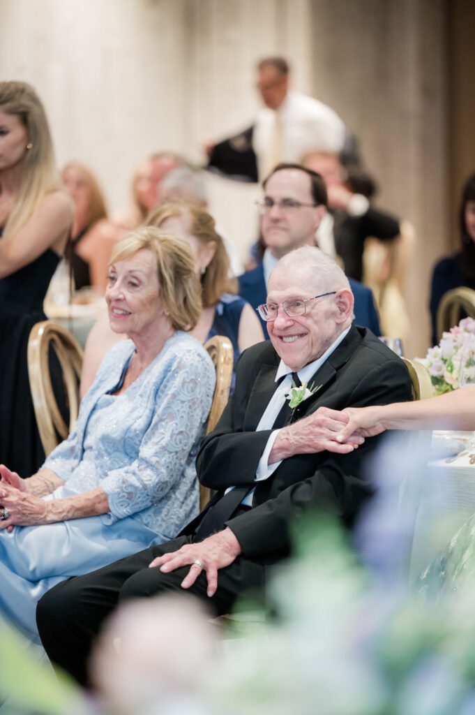Grandparents seated and watching with quiet emotion as their grandchildren share their first dance during a wedding reception at Middleton Place, surrounded by warm evening light and an elegant outdoor celebration atmosphere.