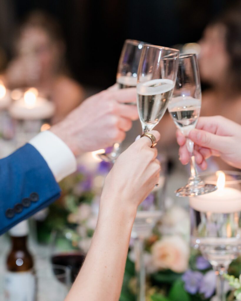 Champagne glasses clinking during a wedding toast at Middleton Place, capturing a joyful moment of celebration between newlyweds and guests.