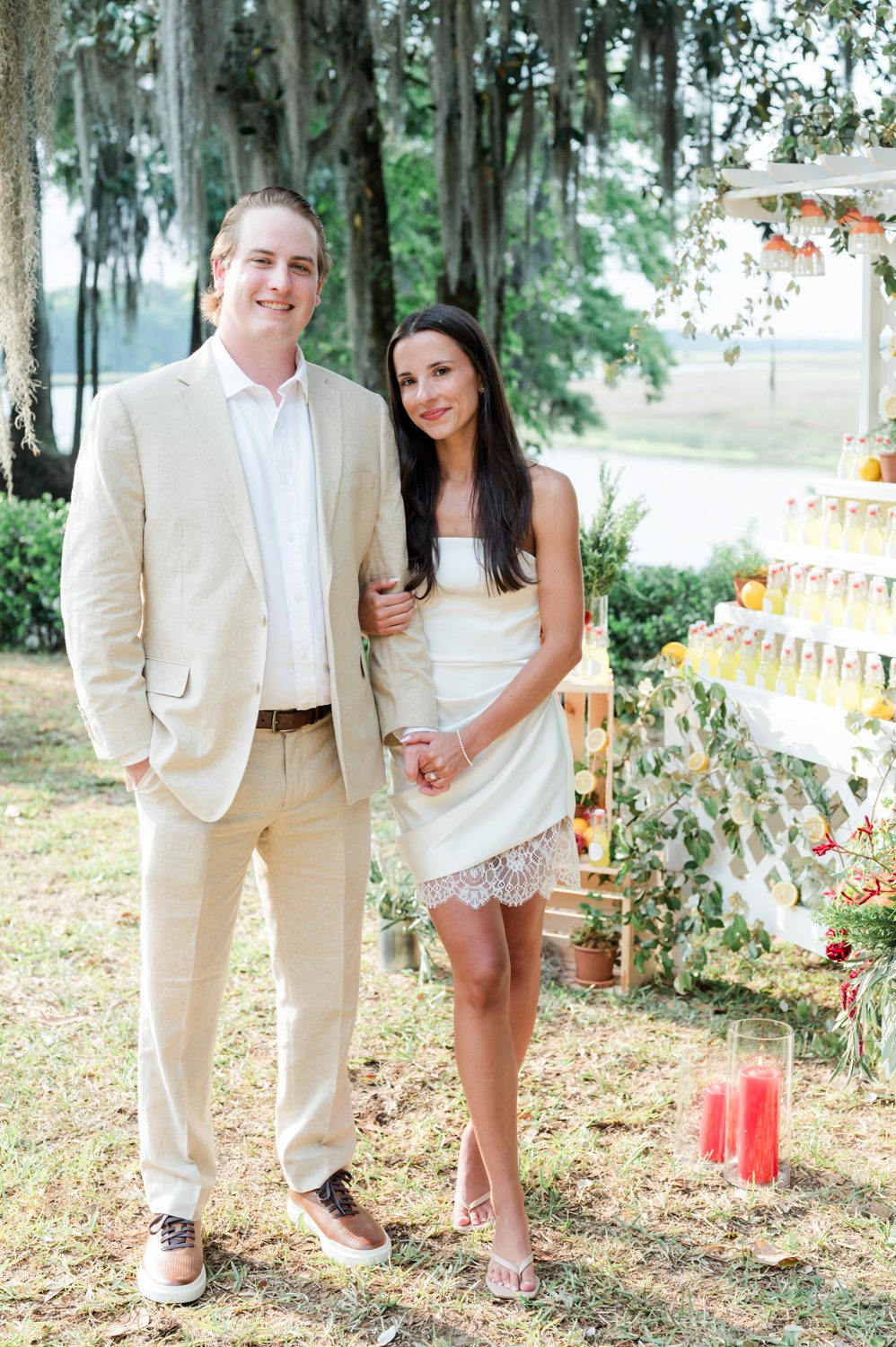Engaged couple holding hands in front of a Limoncello stand at an Italian-themed rehearsal dinner, surrounded by warm, celebratory details and an intimate evening atmosphere.