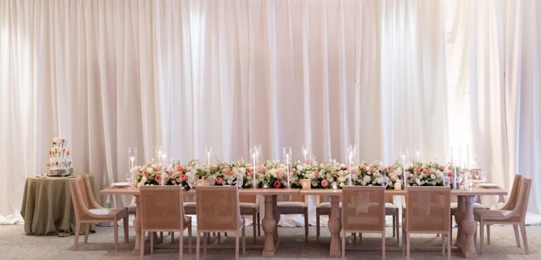 Seapines wedding reception tablescape featuring lit candles, lush floral arrangements, and wooden chairs in a warm coastal setting.
