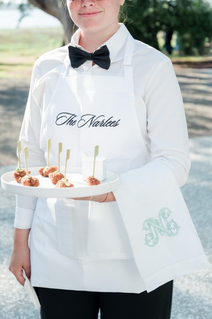 waiter at Lowndes wedding holding tray of appetizers with an embroidered monogrammed towel hanging over arm.