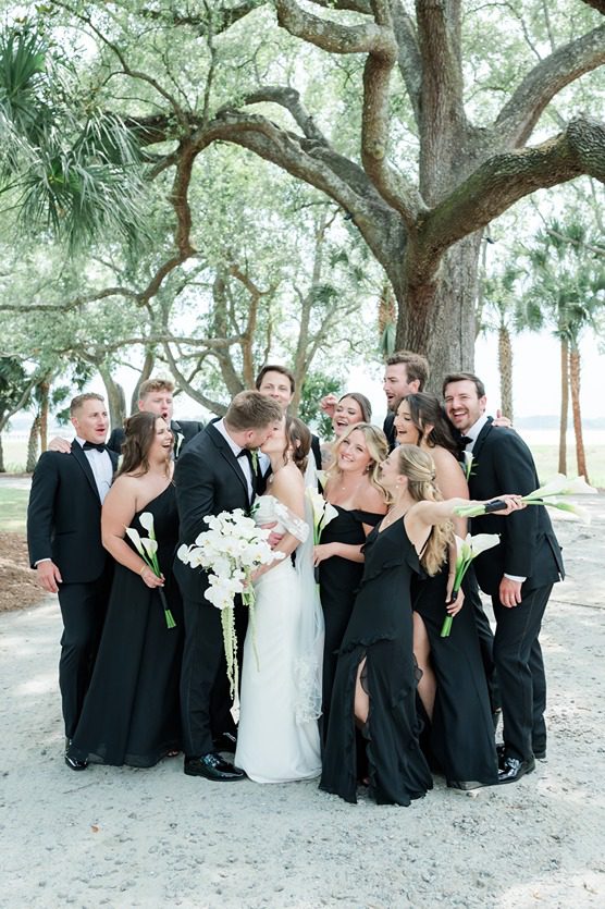 full wedding party loving on newlyweds under oak trees