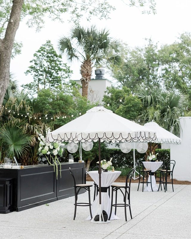 Cocktail hour setup including bar and tables with umbrellas on patio at Lowndes Grove venue