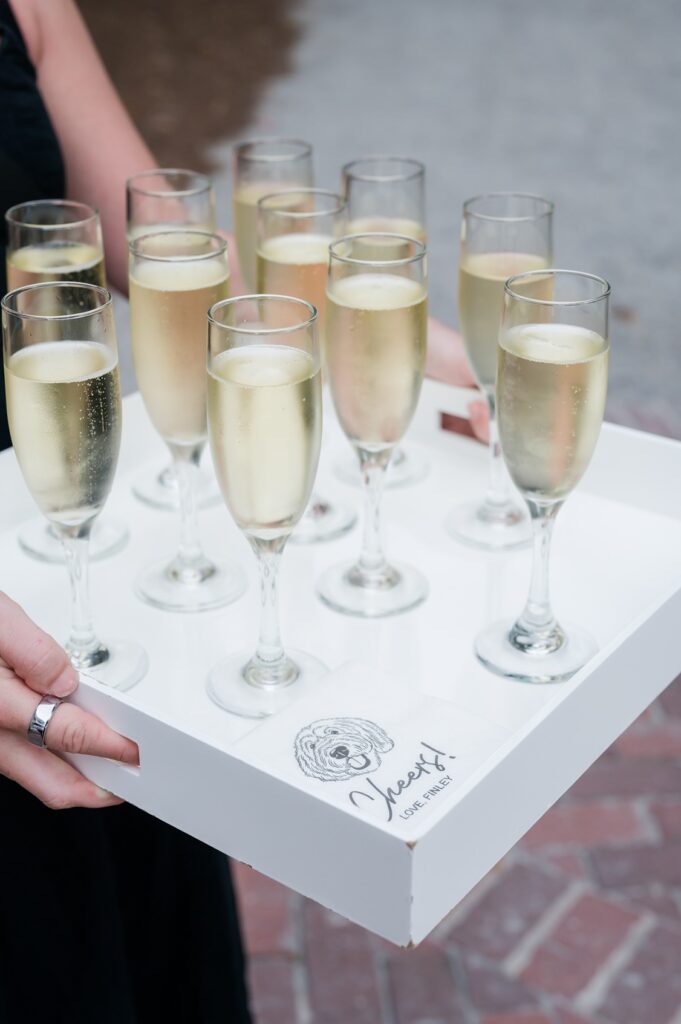 tray of champagne for wedding guests with napkin with dog's face on it