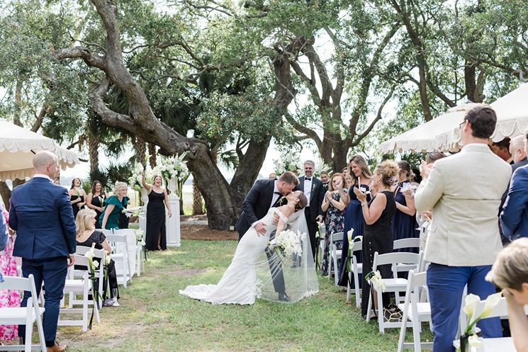 newlyweds kiss and dip while recessing down wedding aisle