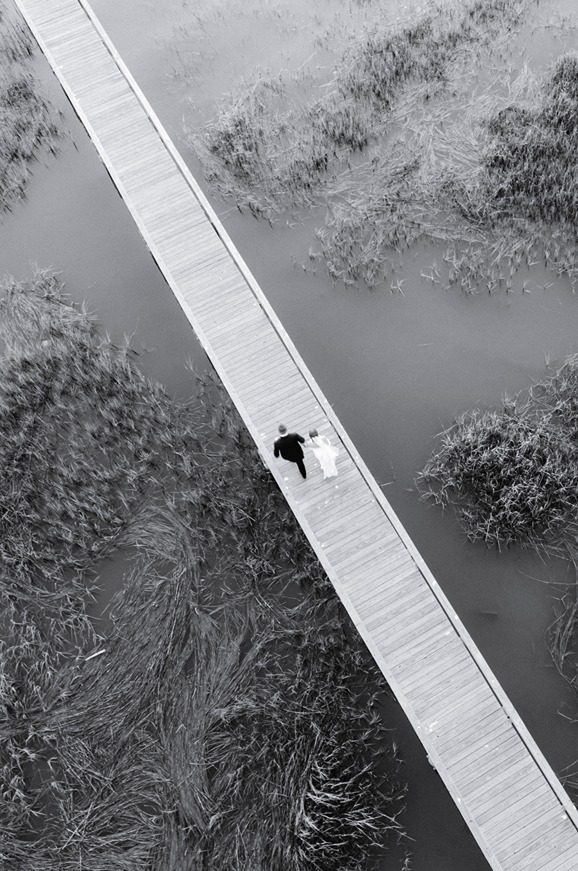black and white Drone photo of couple walking down dock at Lowndes Grove wedding venue in Charleston